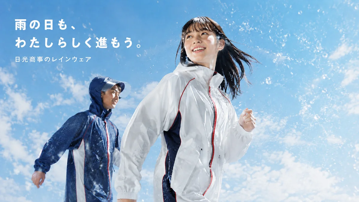 日光商事のレインウェアを着て雨の中を走る女子学生と男子学生